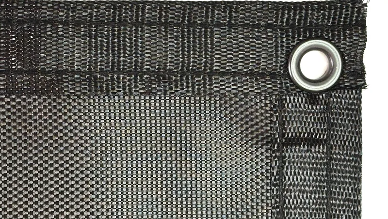Close-up of iron mesh polypropylene dump truck tarp material showing tight 95% closed weave pattern with grommet and reinforced hem