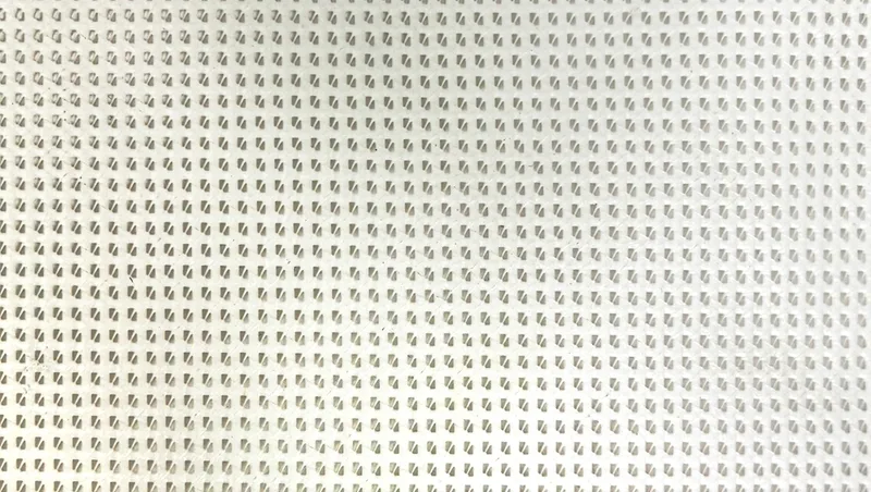 Close-up of white Maxi Mesh PVC coated polyester dump truck tarp material showing tight 72% closed weave pattern